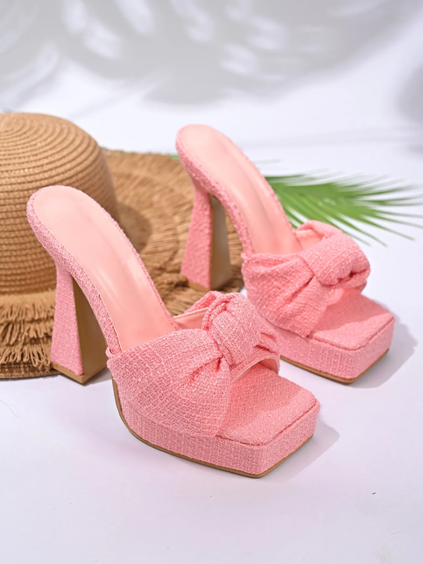 Pink high-heeled shoes with bow details on a white background
