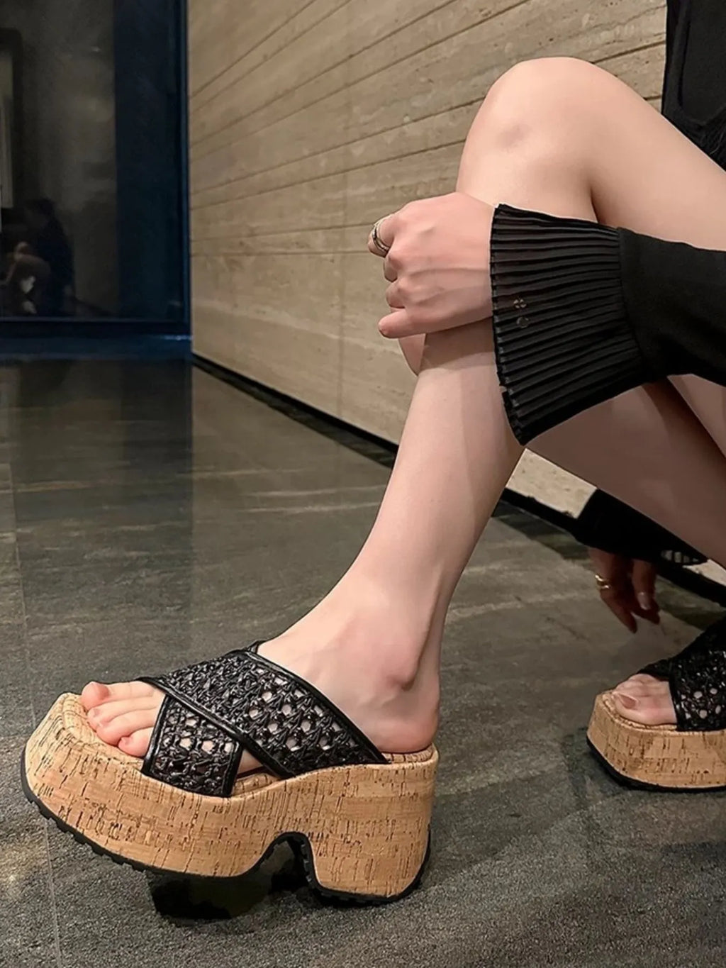 Person wearing black platform sandals with cork sole on a reflective floor-blackorvani.com