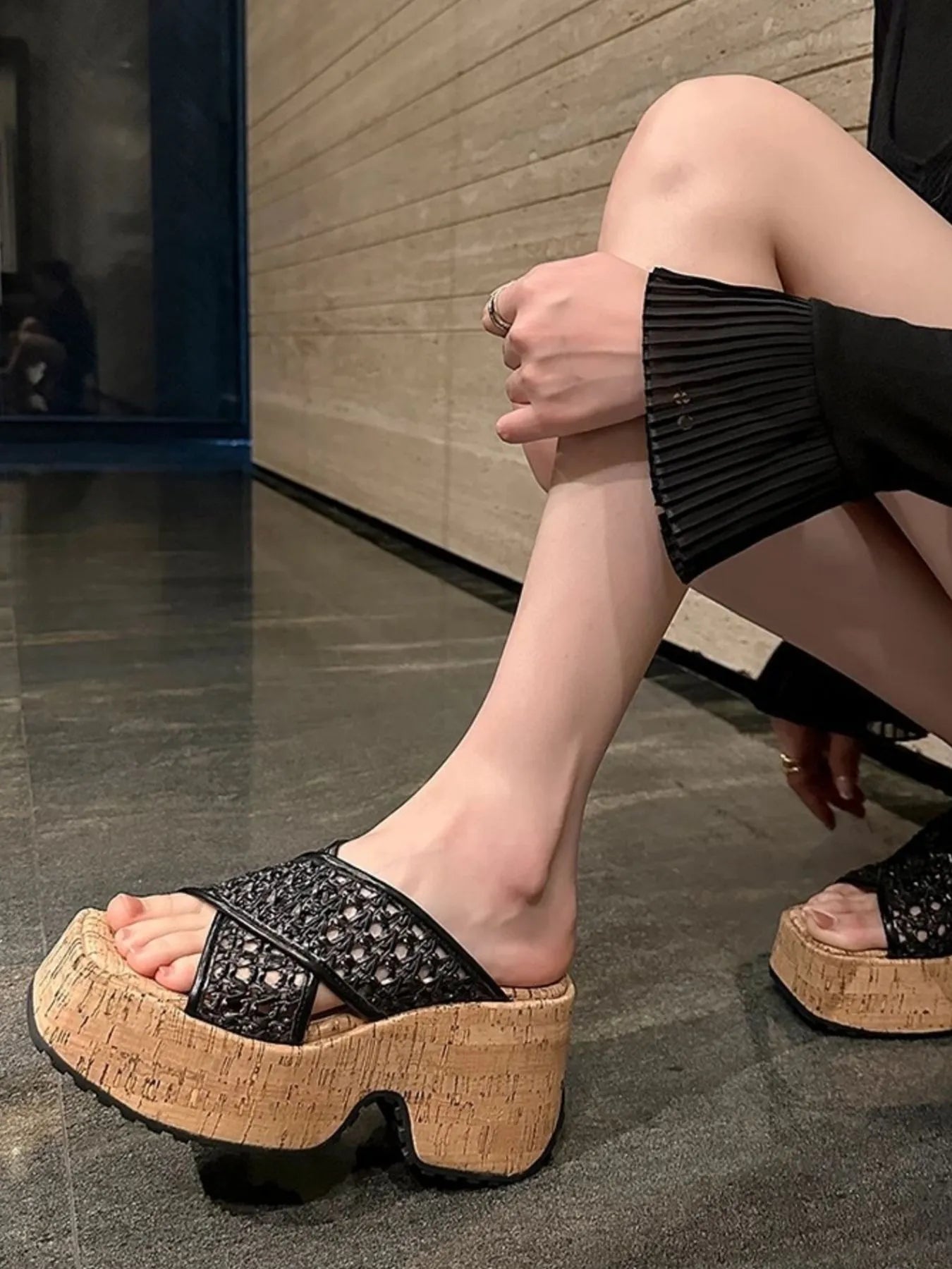Person wearing black platform sandals with cork sole on a reflective floor-blackorvani.com