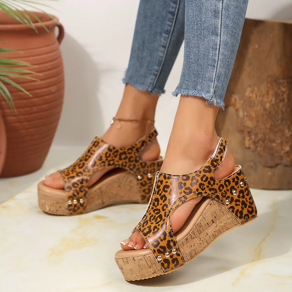 Leopard print sandals with cork wedge sole worn with blue jeans on a light background
