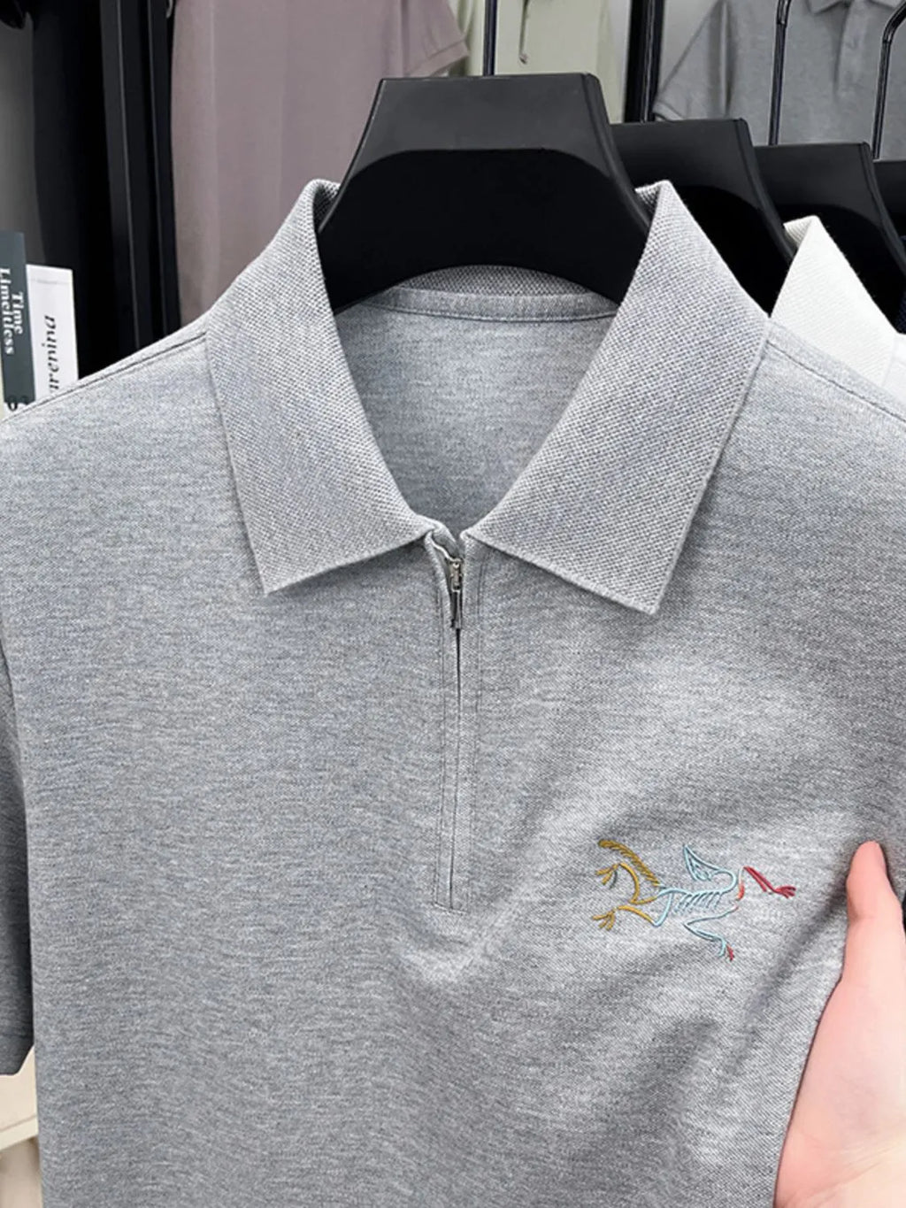 Gray polo shirt with a small embroidered design on a hanger-blackorvani.com