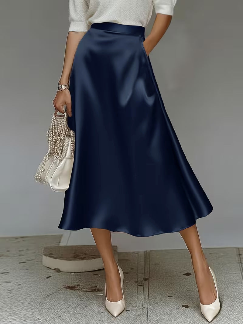 Person wearing a navy satin skirt with a plain background