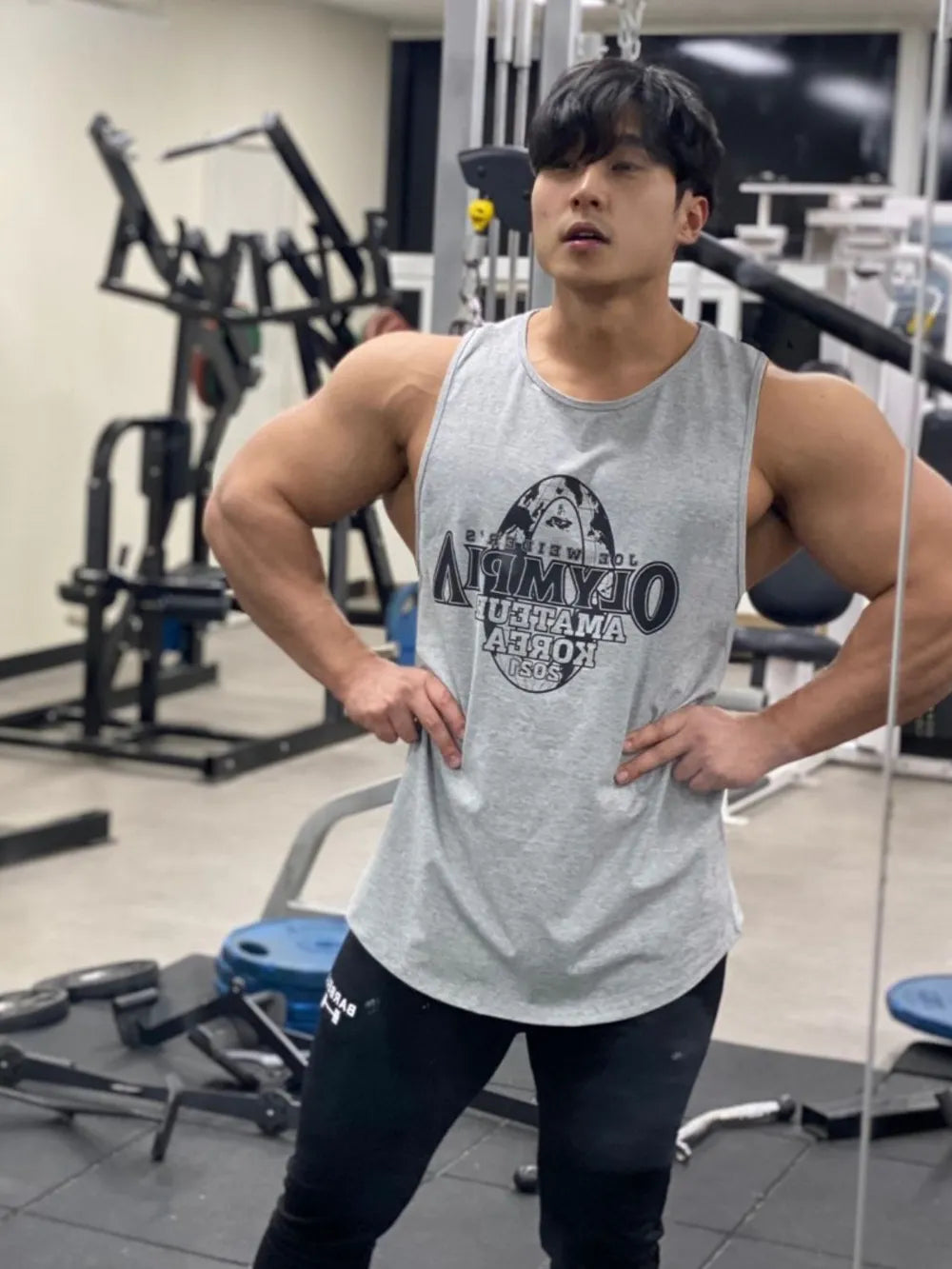 Person wearing a gray tank top with branding in a gym setting-blackorvani.com