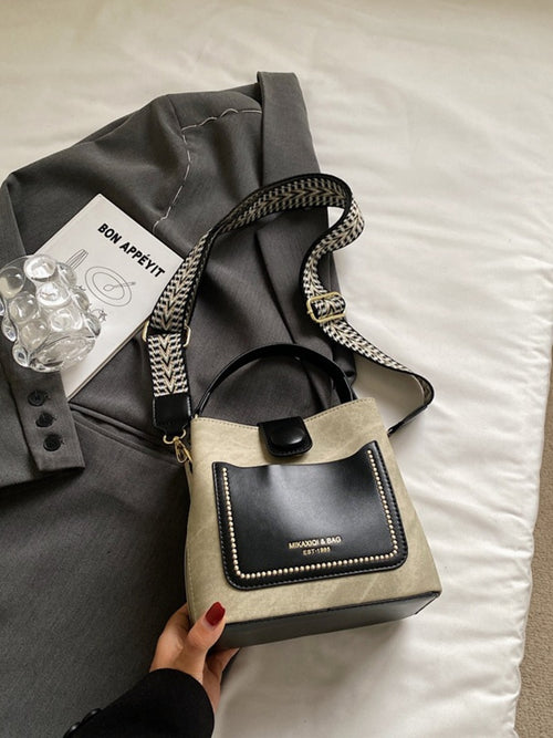 Handbag with black flap and beige body on a bed with a gray jacket and card-BlackOrvani