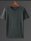 Green textured t-shirt on a wooden hanger against a gray background