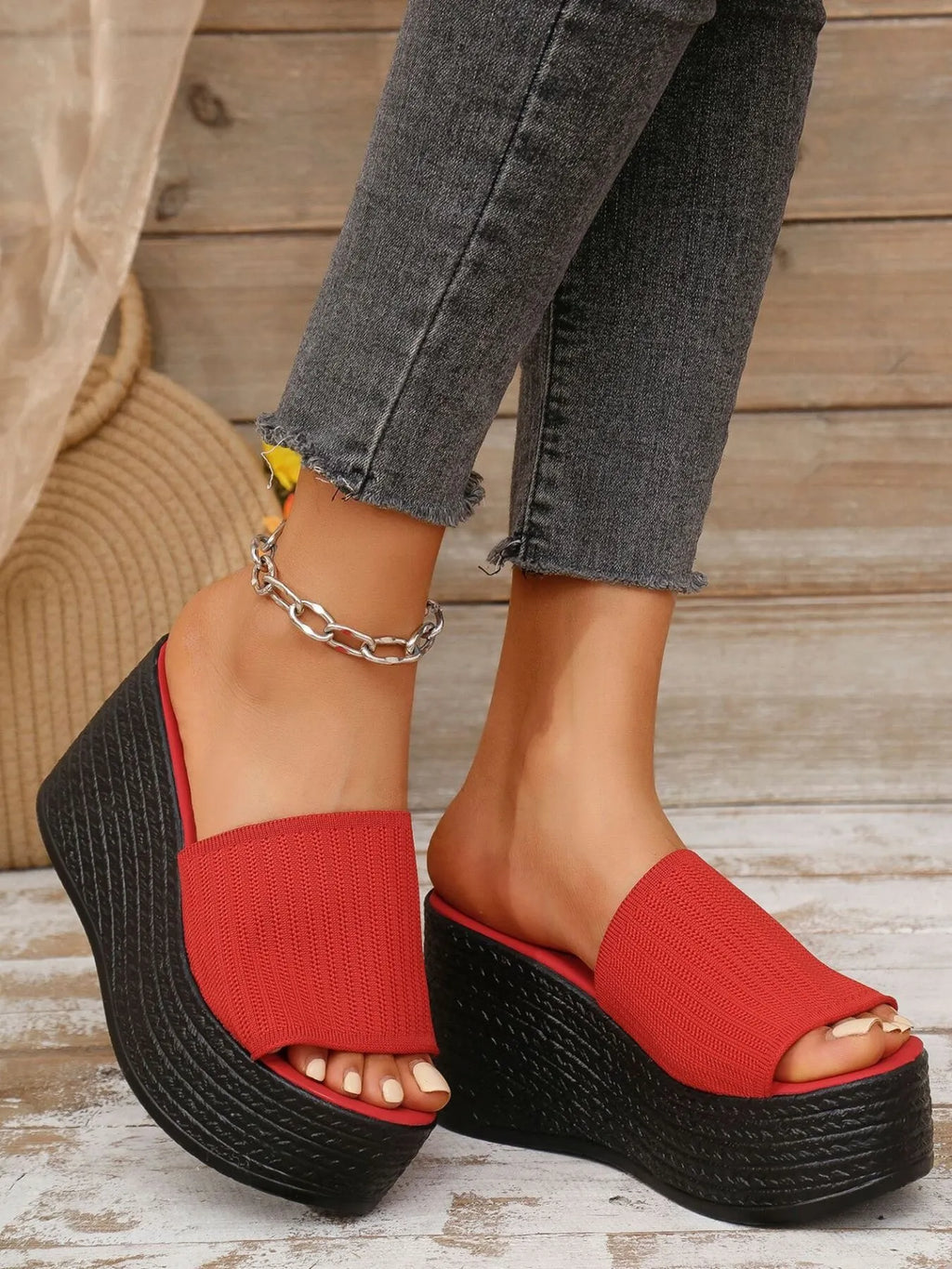Red platform sandals worn with gray jeans on a wooden floor.
