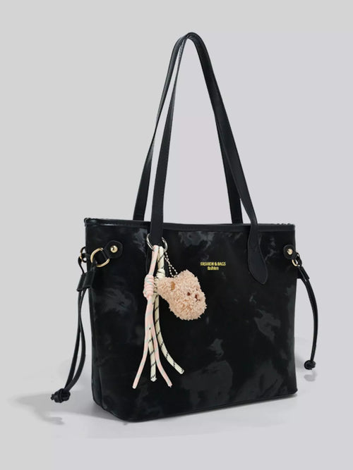 Black handbag with decorative pom-pom charm on a light gray -White handbag with a heart-shaped charm held by a person wearing a black coat-Black saddle bag with a gray cover on a white surface background-White handbag with a heart-shaped charm held by a person wearing a black coat-Black saddle bag with a gray cover on a white surface-BLACKOrVaNi
