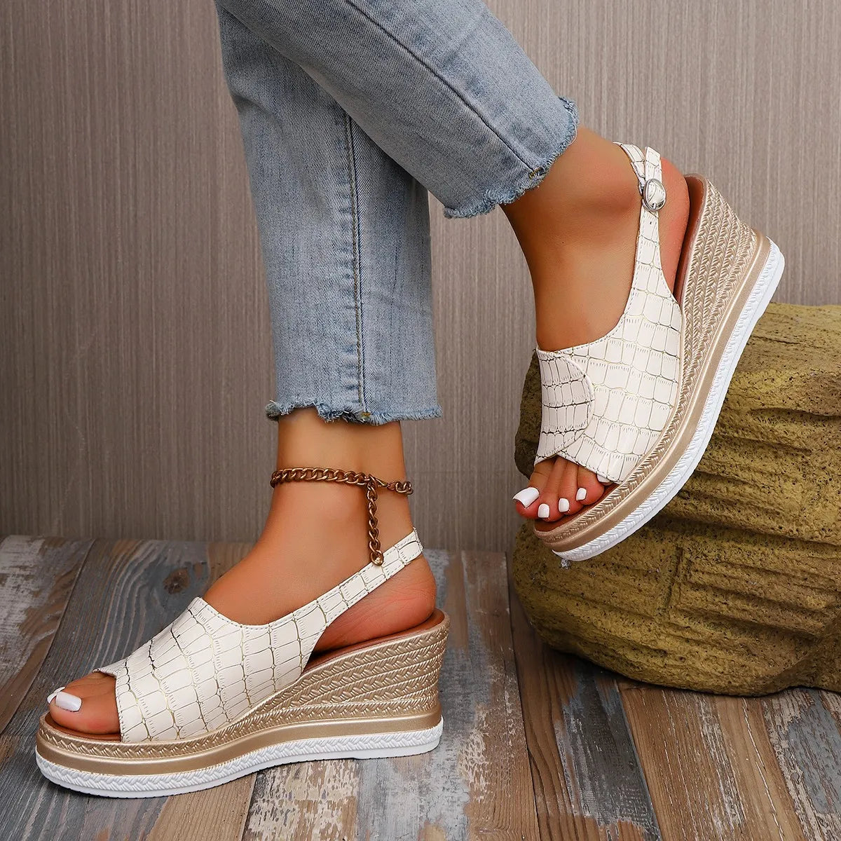 White wedge sandals with brown soles worn by a person sitting on a wooden floor.-blackorvani.com