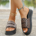 Brown patterned sandals worn on feet with accessories, blurred background