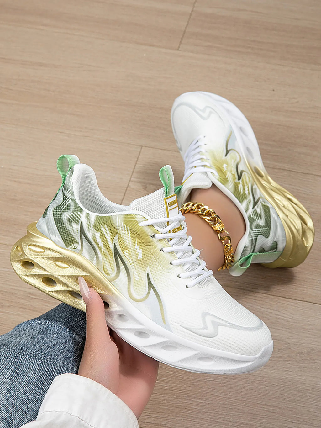 White sneakers with gold and green design on a wooden floor