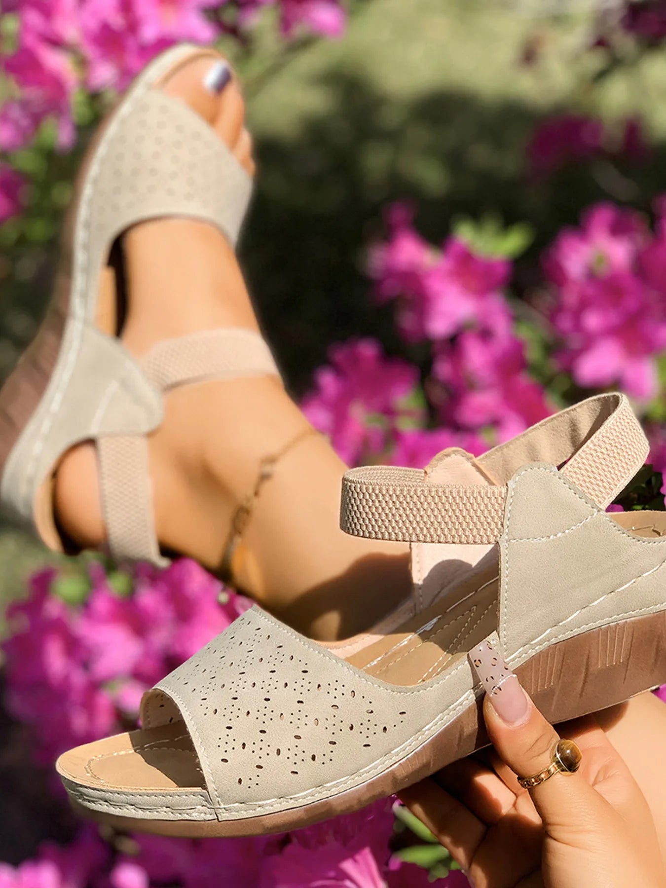 Beige wedge sandals worn with a blurred floral background