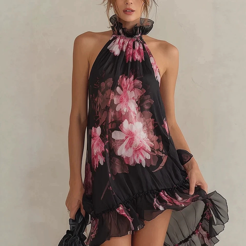 Woman wearing a black halter neck dress with pink floral patterns on a plain background