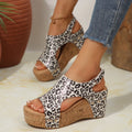 Leopard print wedge sandals worn with denim jeans on a neutral background