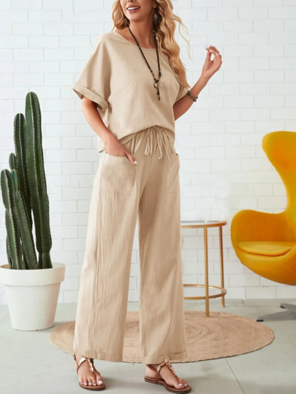 Woman wearing a beige outfit in a room with a cactus and yellow chair-blackorvani
