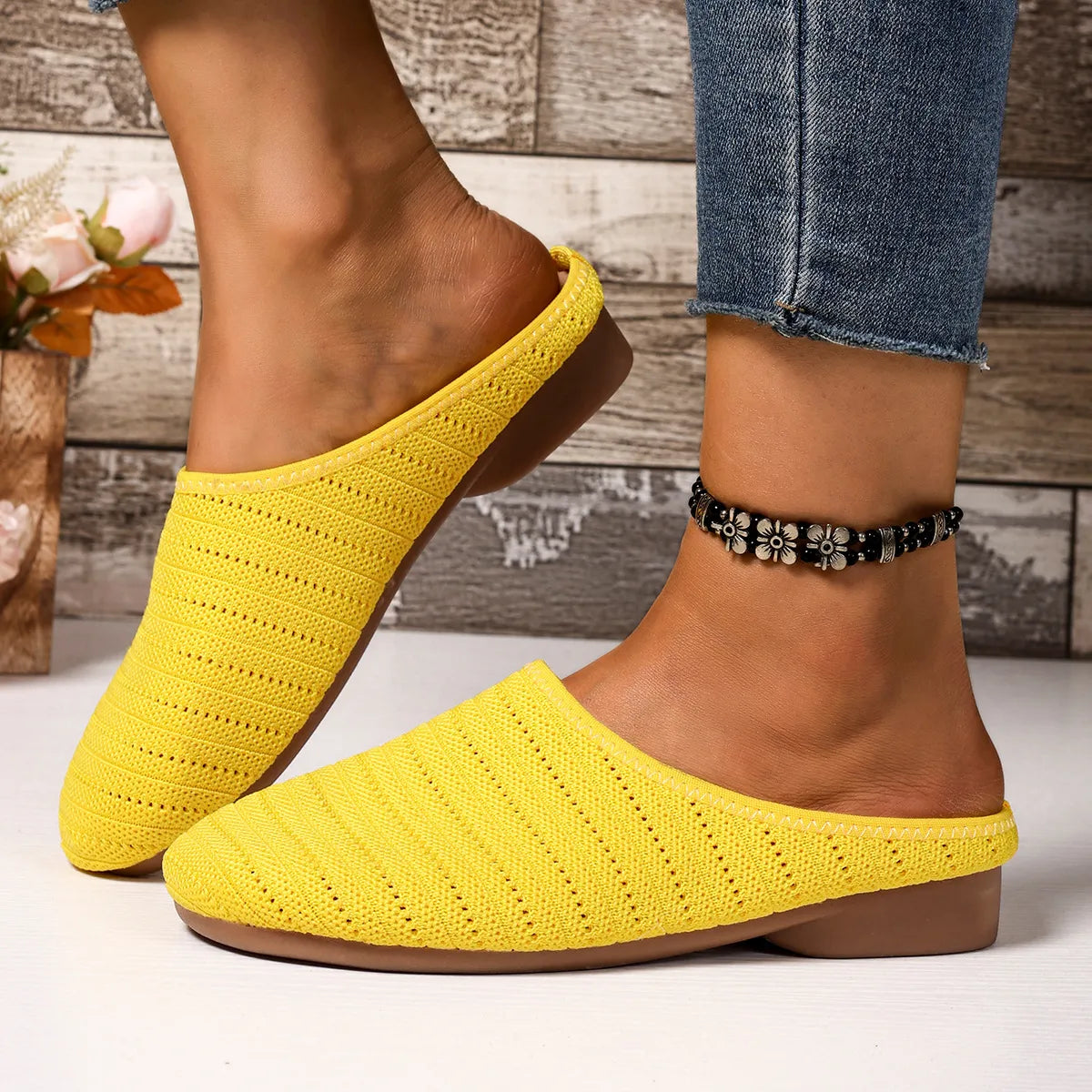 Yellow slippers worn with denim jeans on a wooden floor background