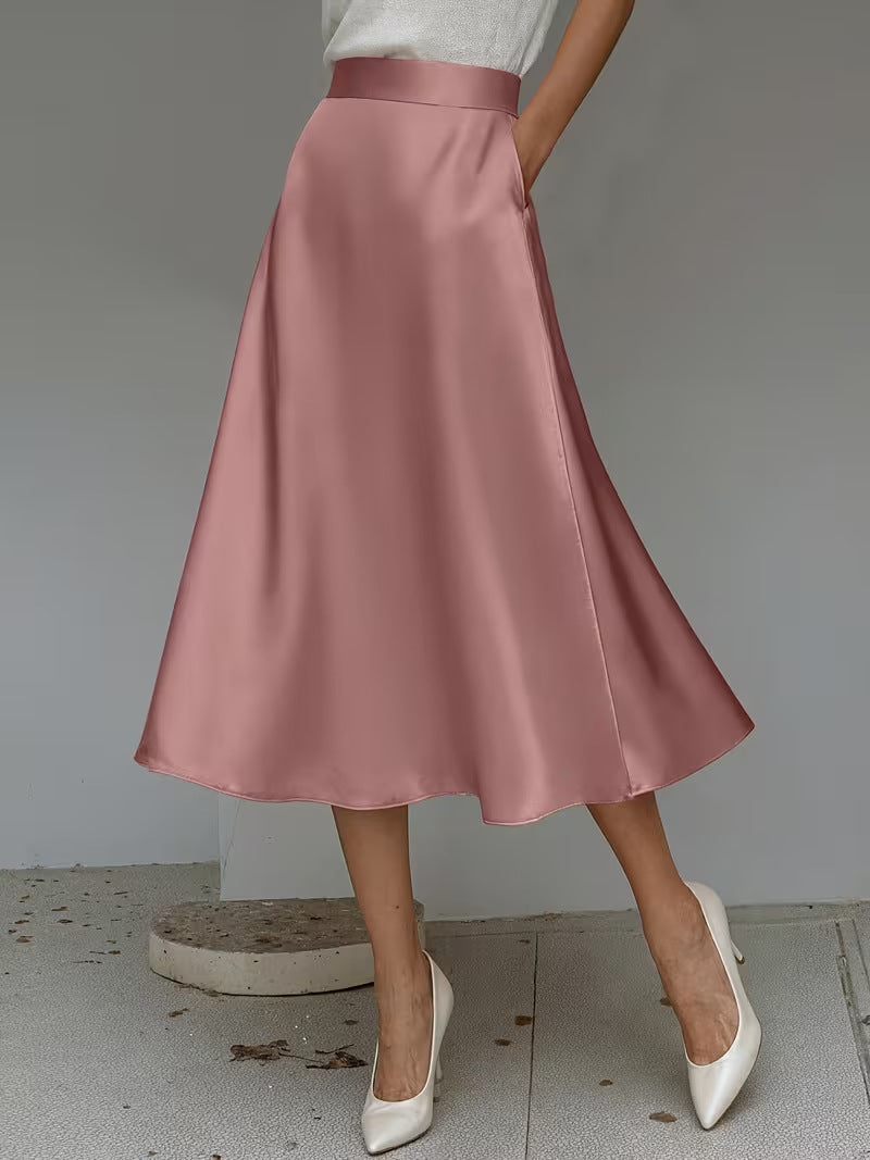 Person wearing a pink satin skirt with white shoes on a plain background