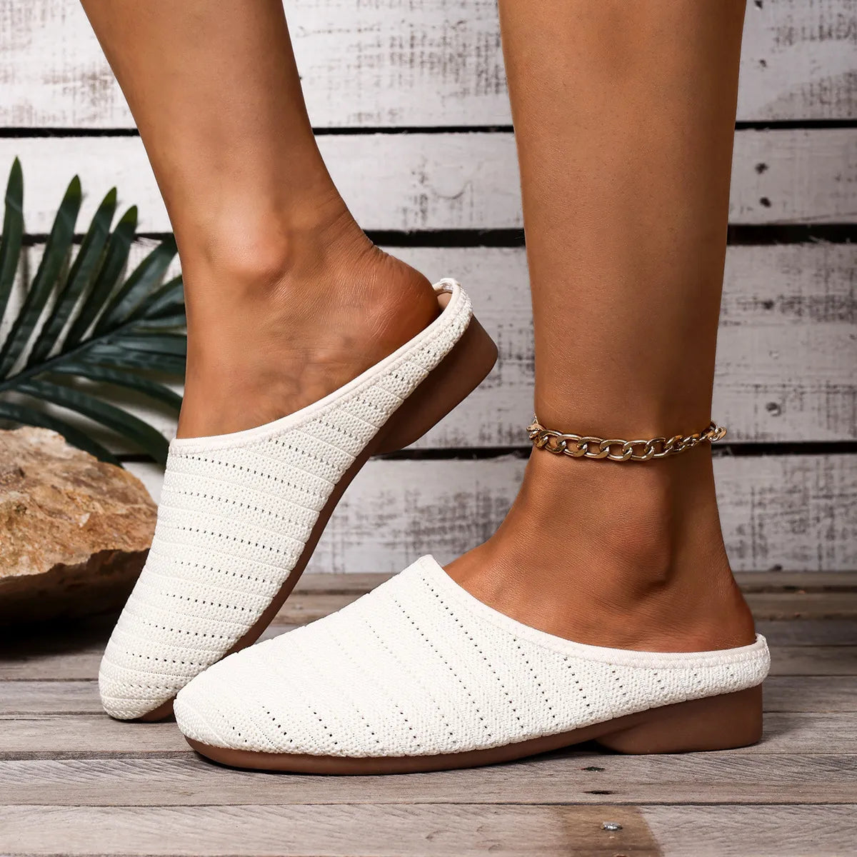 White woven slippers worn by a person on a wooden floor with a rustic background.