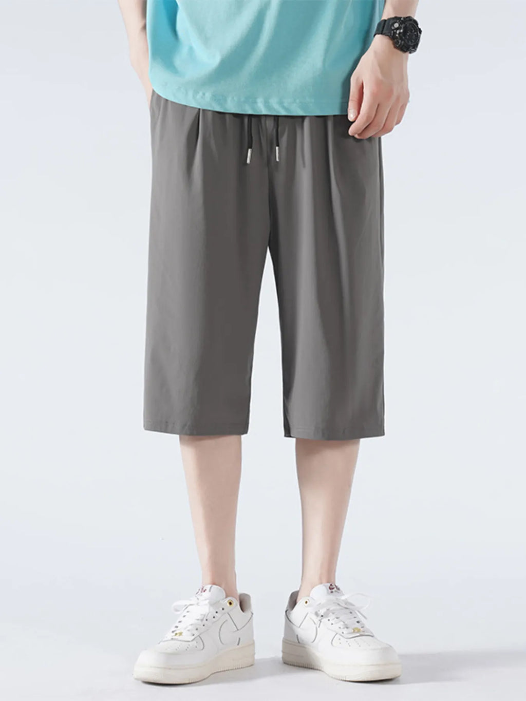 Person wearing gray shorts and white sneakers on a light gray background-blackorvani.com