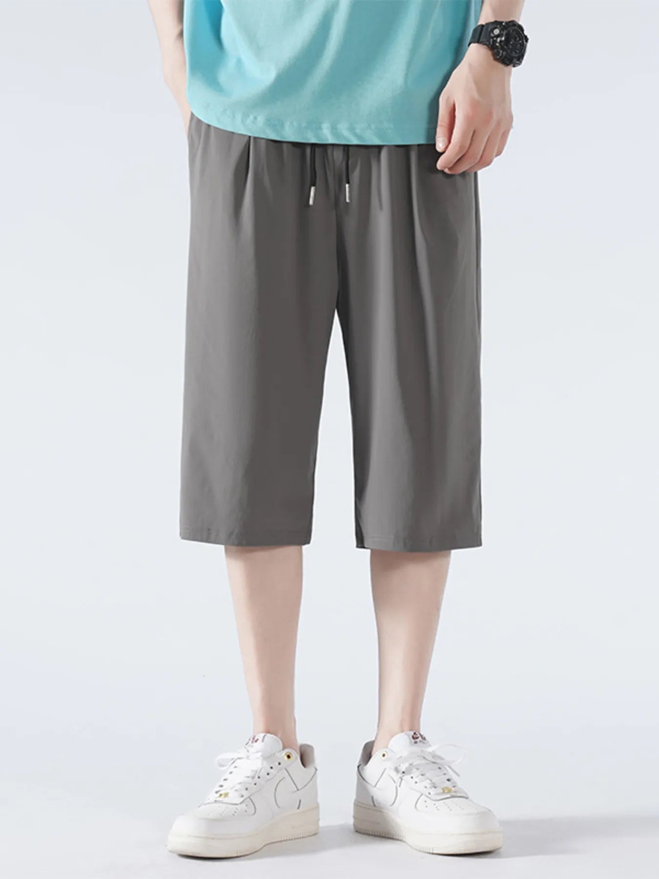 Person wearing gray shorts and white sneakers on a light gray background-blackorvani.com
