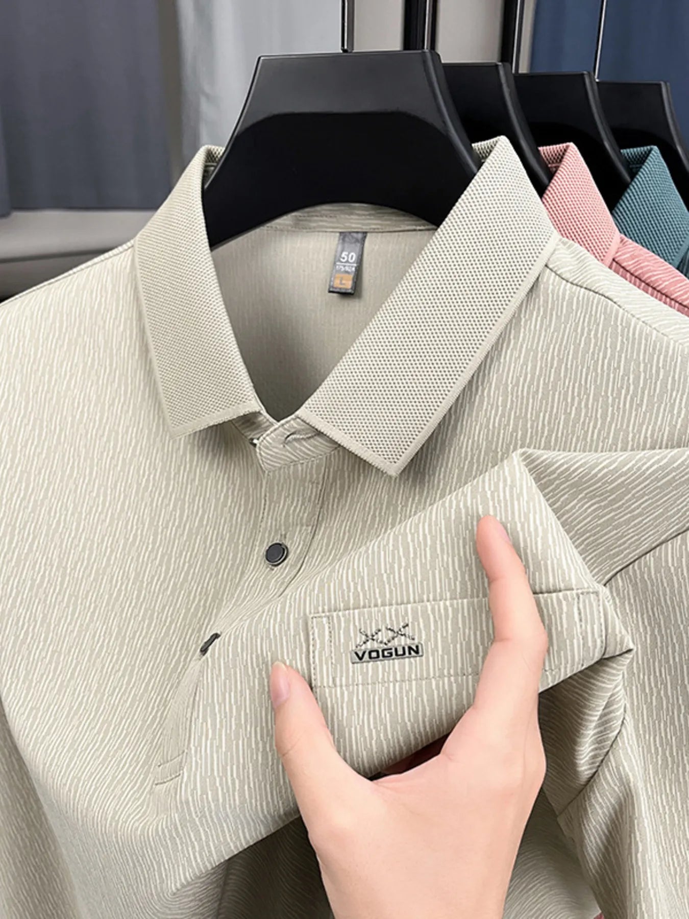 Beige polo shirt with a visible brand logo, held by a hand against a neutral background-blackorvani.com