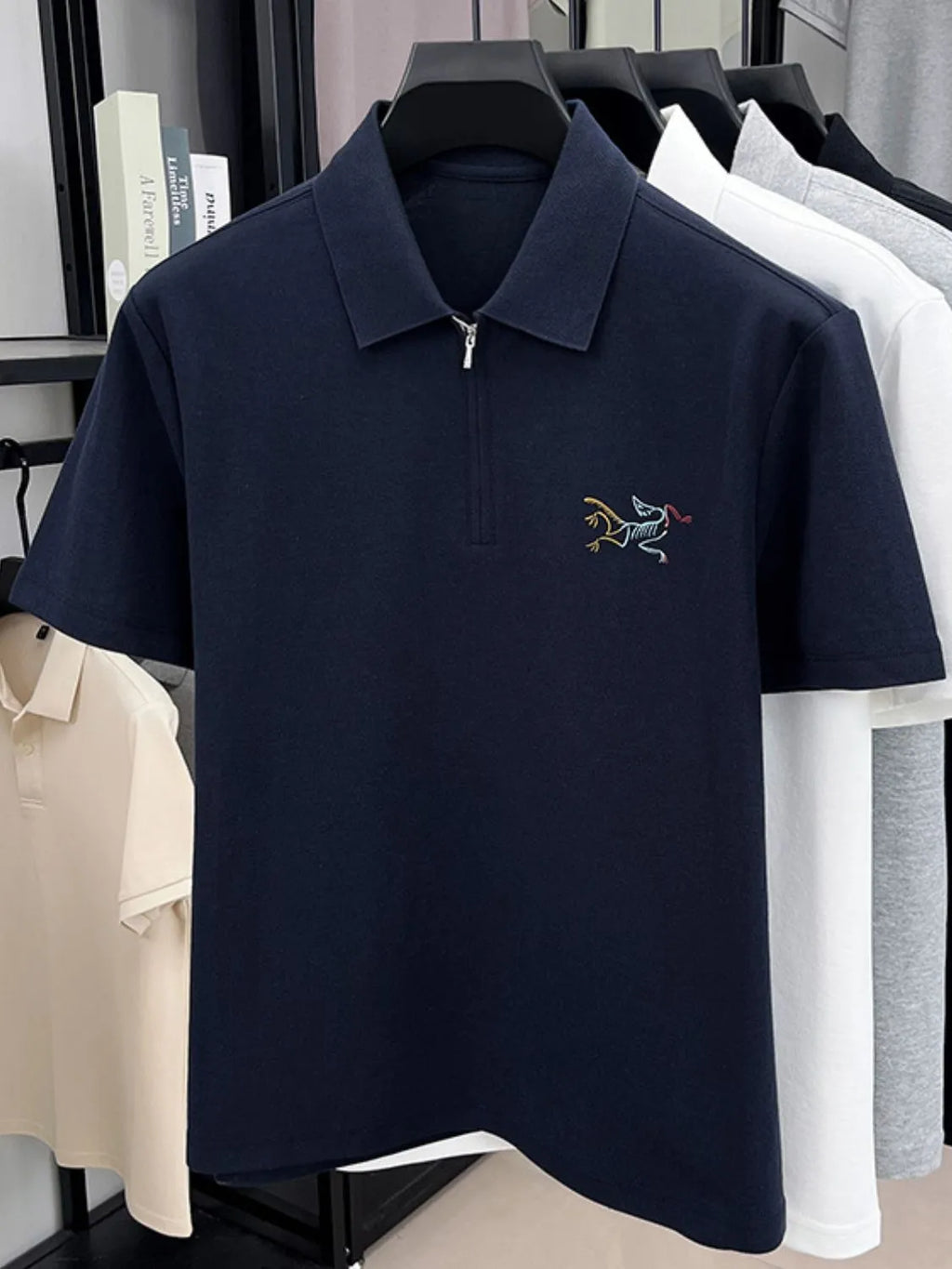 Navy blue polo shirt with a small embroidered design on a rack with other shirts-blackorvani.com