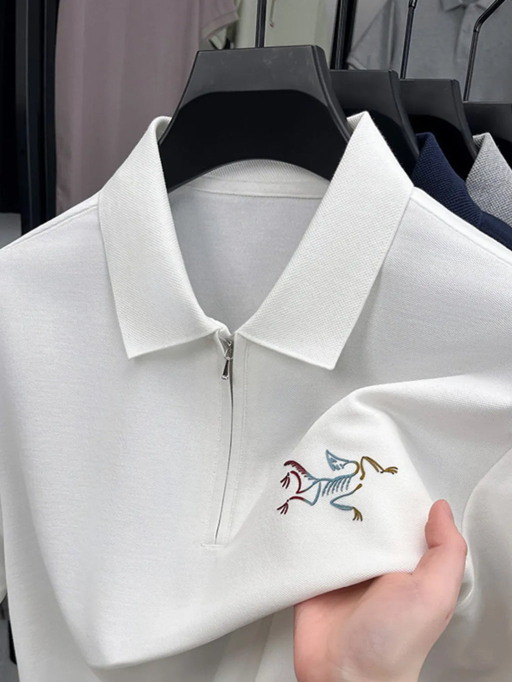 White polo shirt with embroidered design on a hanger-blackorvani.com