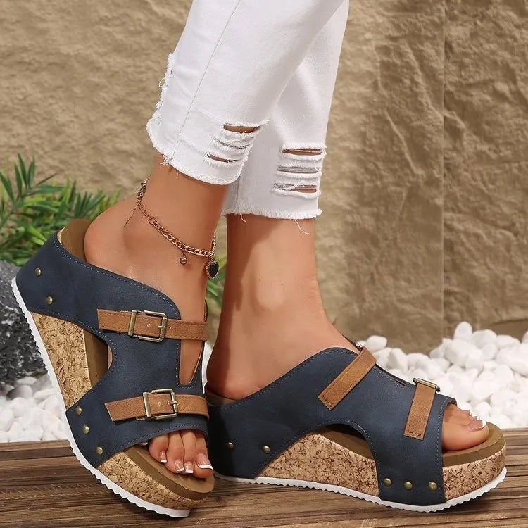 Navy wedge sandals with brown straps worn with white jeans against a natural background