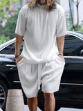 Person wearing a light gray outfit with a car and trees in the background