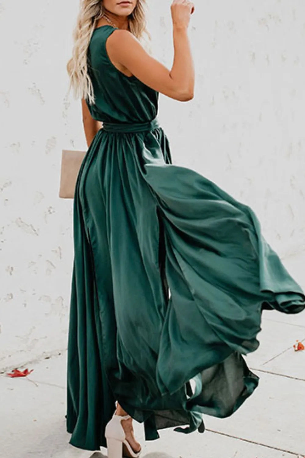 Woman wearing a flowing green dress against a white brick wall-blackorvani.com