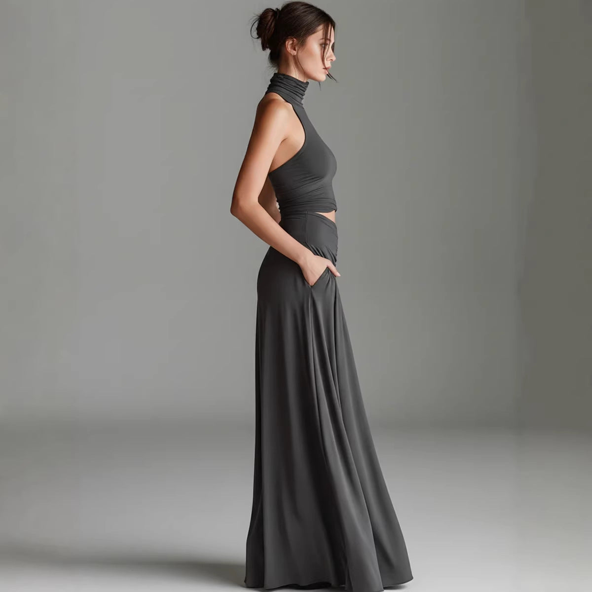 Woman wearing a long dark gray dress against a plain background
