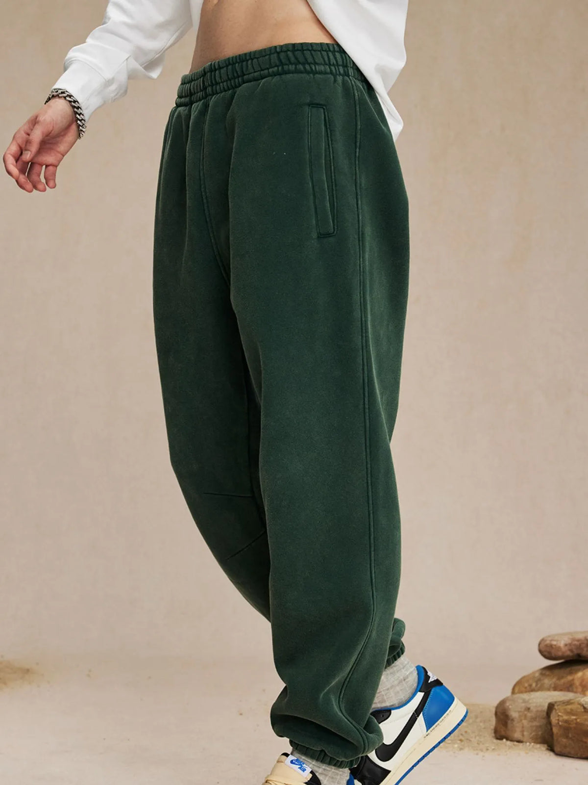 Green sweatpants worn by a person on a beige background-blackorvani.com