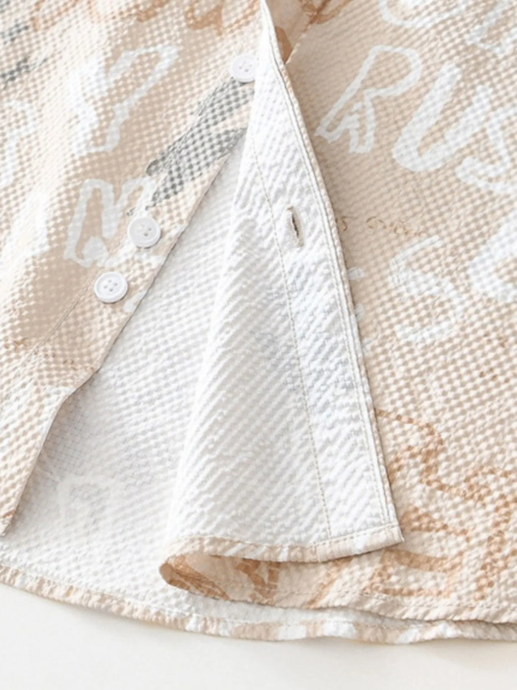 Close-up of a textured beige fabric with white lettering on a white background-blackorvani.com