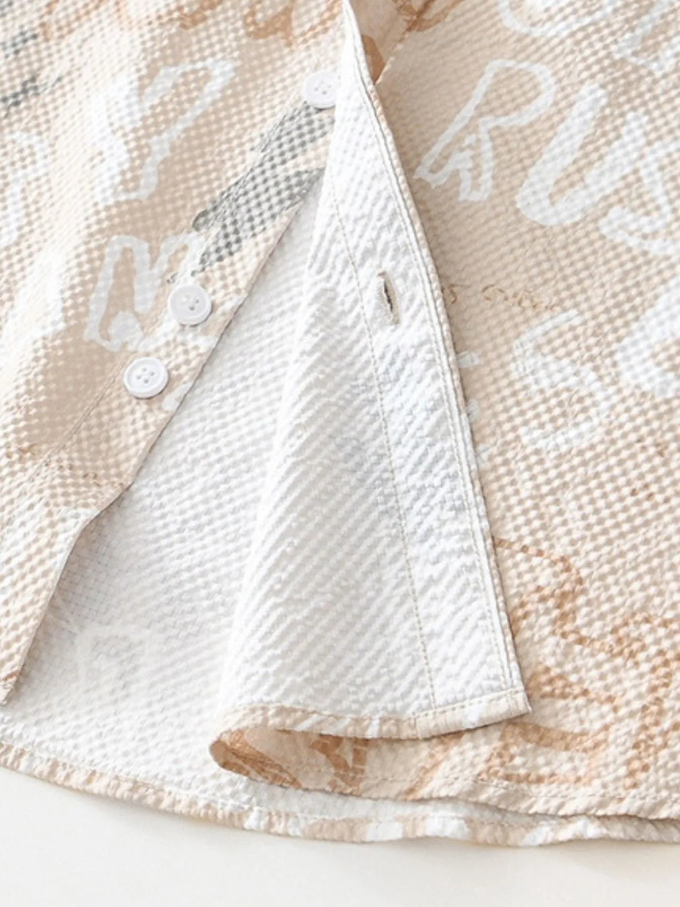 Close-up of a textured beige fabric with white lettering on a white background-blackorvani.com