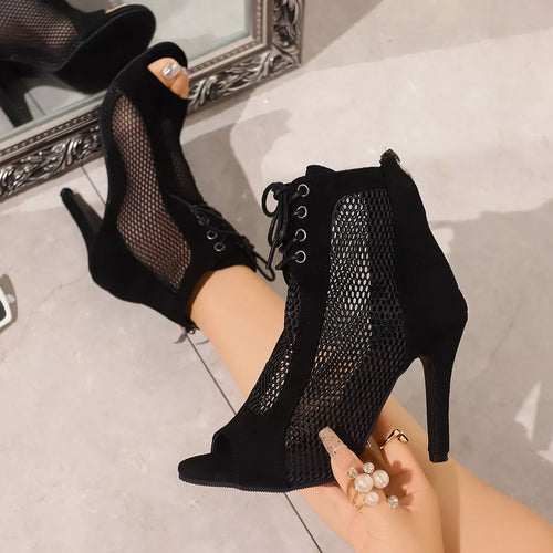 Black mesh high-heeled shoes worn by a person sitting on a light-colored floor-blackorvani.com