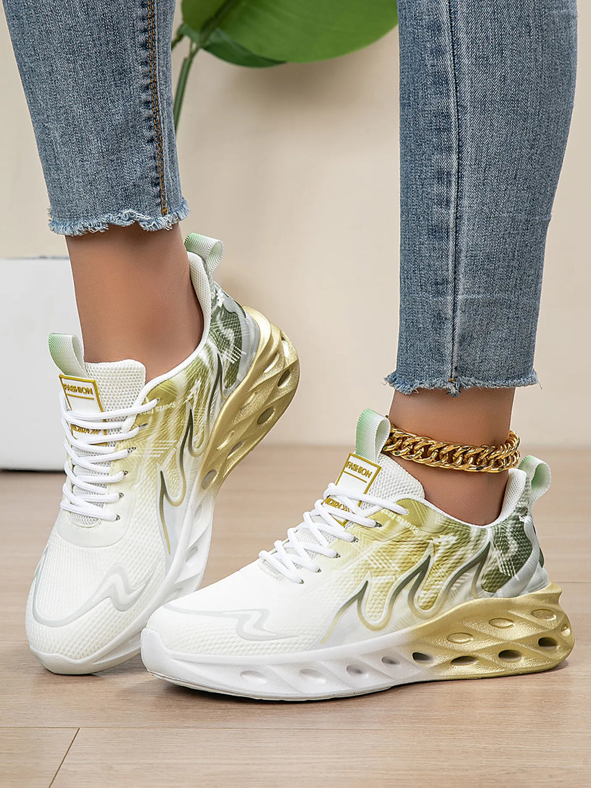 White sneakers with gold accents worn by a person on a wooden floor.