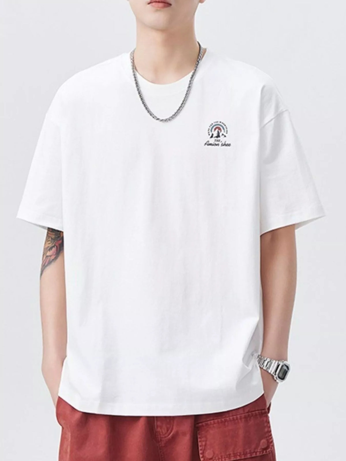 Person wearing a white t-shirt with a small logo and red pants on a light gray background-blackorvani.com