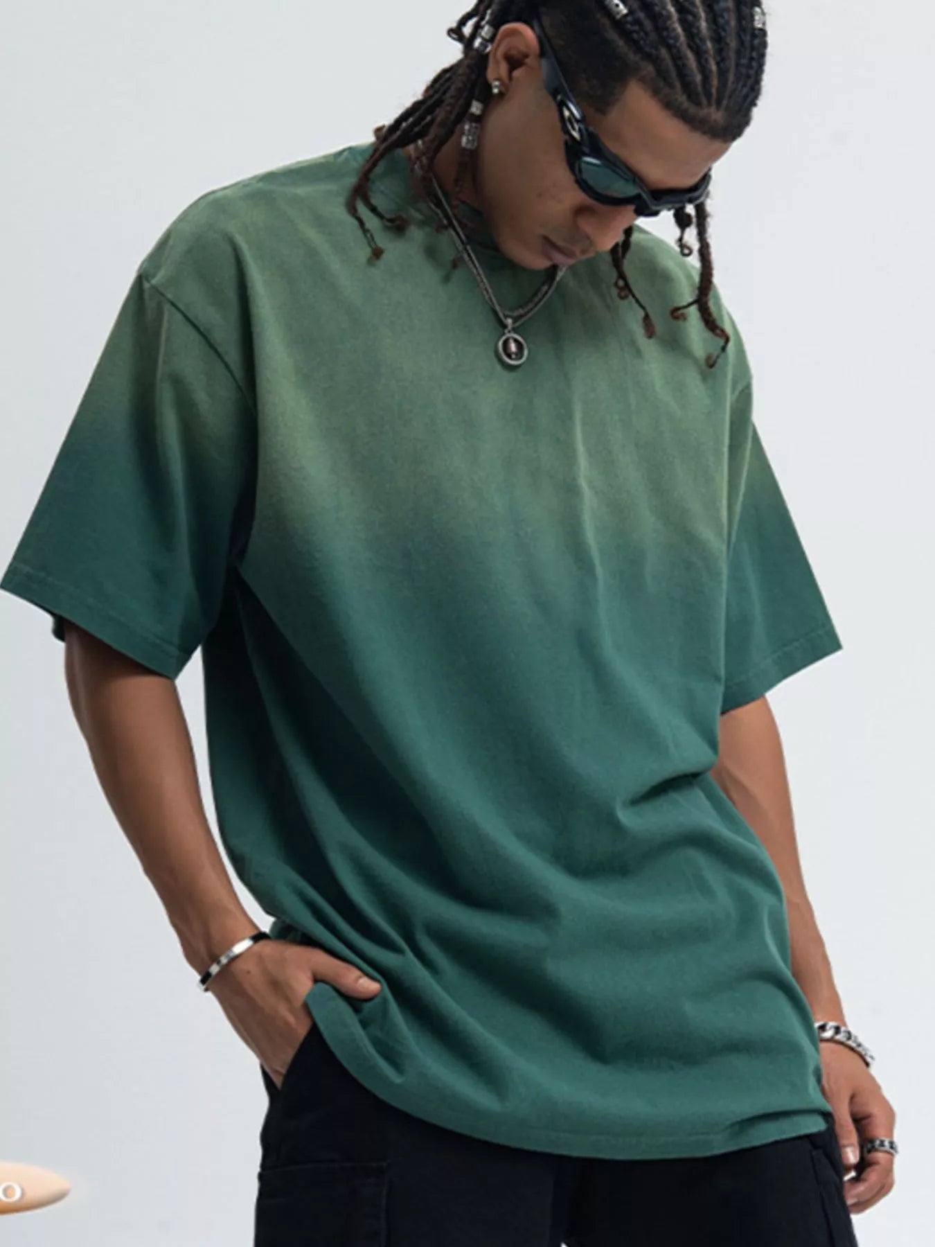 Person wearing a green t-shirt and sunglasses on a plain background-Blue denim skirt worn by a person with a blurred background-blackorvani.com