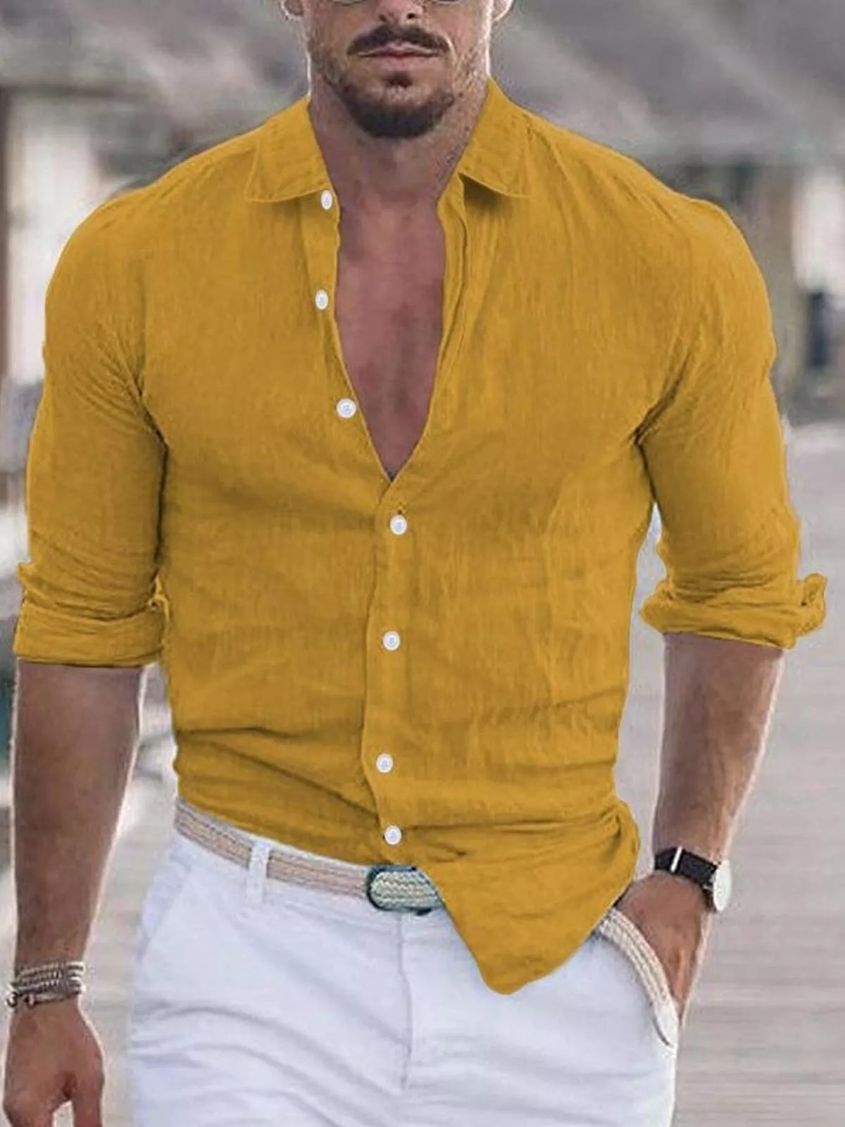 Man wearing a mustard yellow button-up shirt with rolled-up sleeves and white pants.