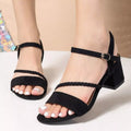Black strappy block-heel sandals with braided straps and ankle buckles, shown on a model's feet against a neutral beige background-blackorvani.com