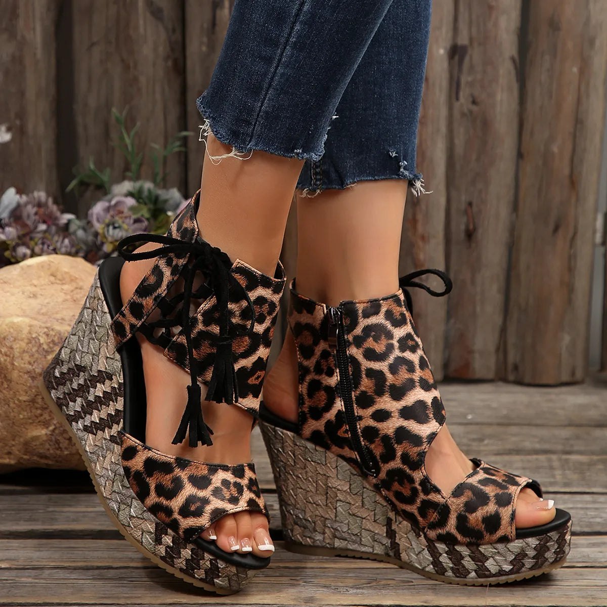 Leopard print wedge sandals worn with denim shorts on a wooden floor.