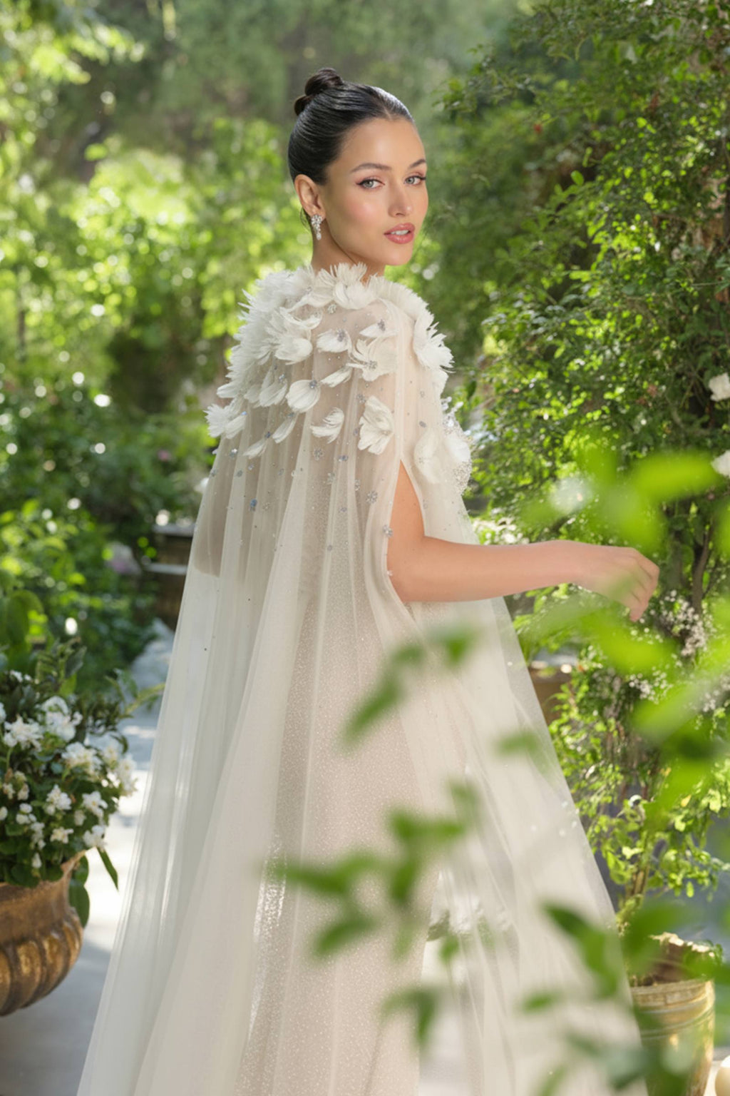 Woman in a white wedding dress with floral cape outdoors