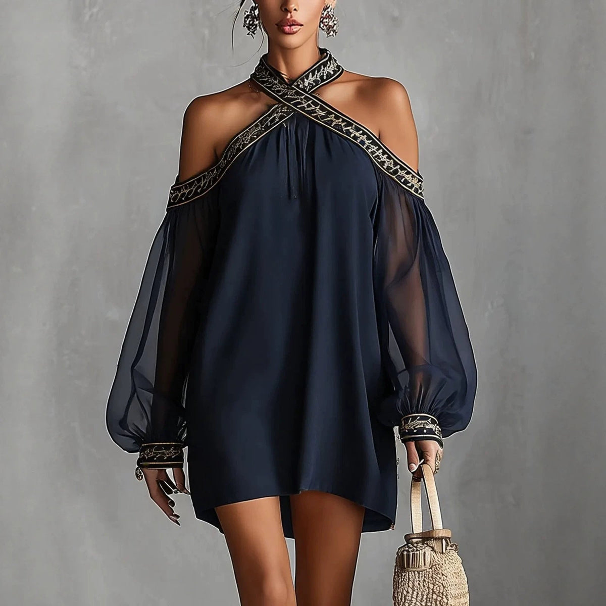 Woman wearing a dark blue dress with sheer sleeves against a gray background