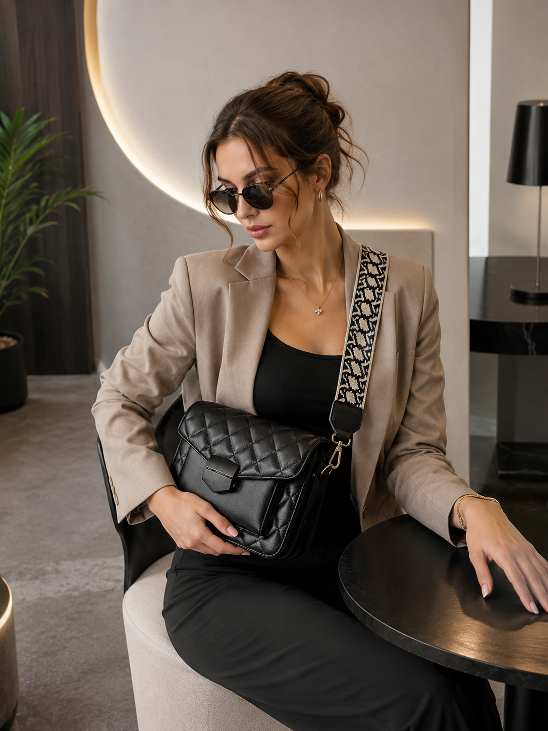 A woman holding a black quilted shoulder bag with a patterned strap-BlackOrvani