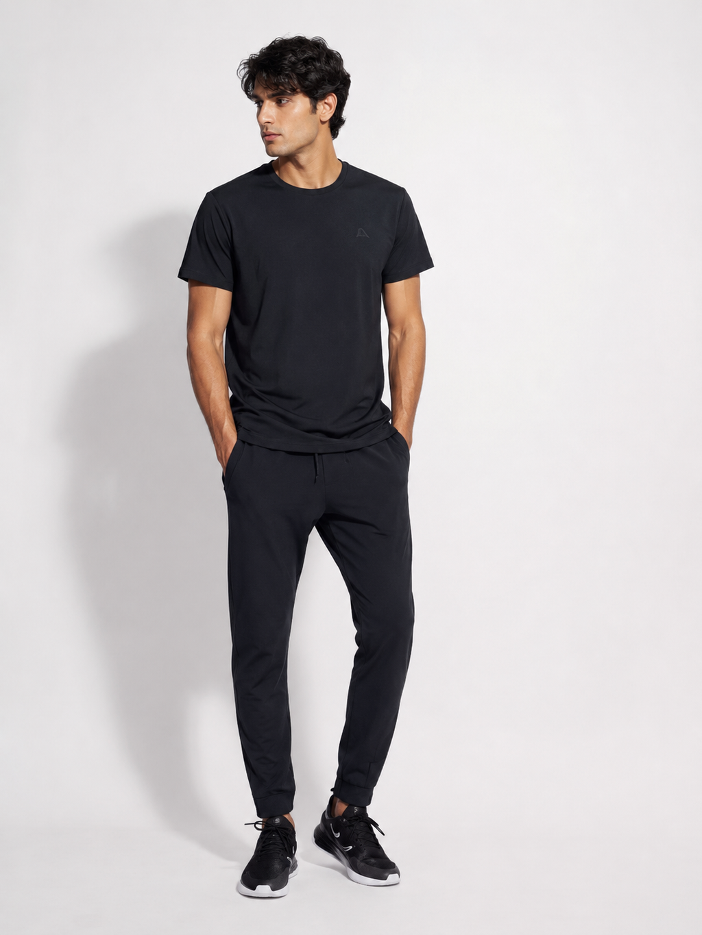 Men's black jogger pants worn by a male model with black sneakers on a clean studio background-BlackOrvani