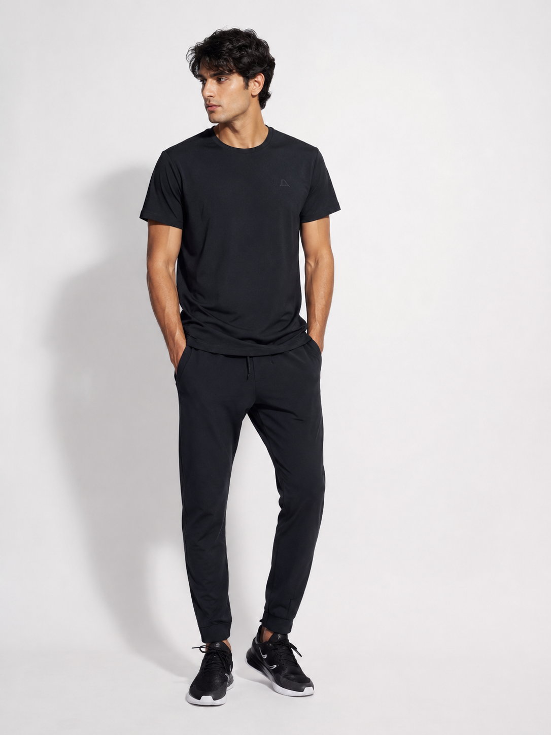 Men's black jogger pants worn by a male model with black sneakers on a clean studio background-BlackOrvani