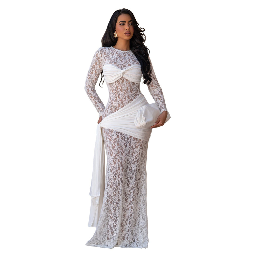 A woman modeling a long-sleeve white lace maxi dress with a sweetheart neckline, a twisted front detail, and a draped sash at the waist, shown against a plain white background.
