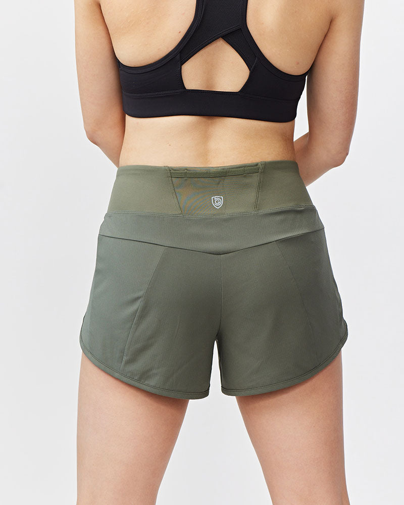 Person wearing green athletic shorts and black sports bra on a light gray background