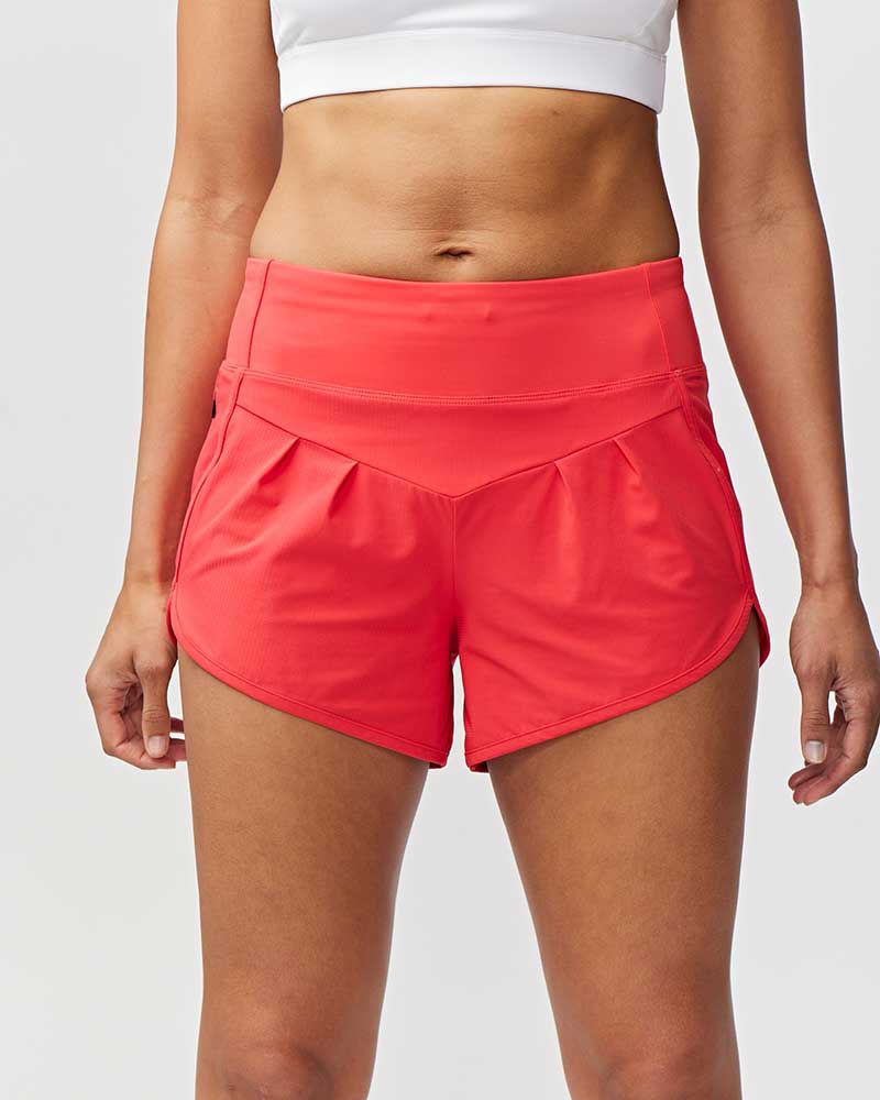 Person wearing bright pink athletic shorts on a light gray background