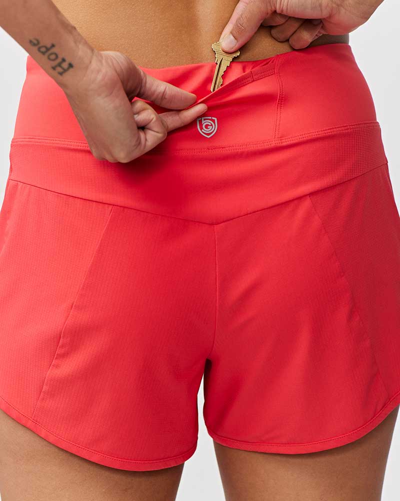 Person wearing red athletic shorts with a brand logo on a plain background