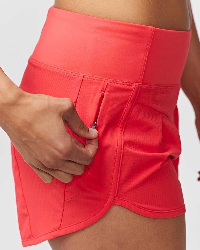 Person wearing a bright pink athletic skirt with a hand in one of the pockets.